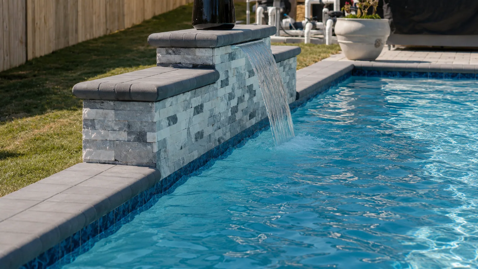 Sheer descent water feature spilling into a custom pool